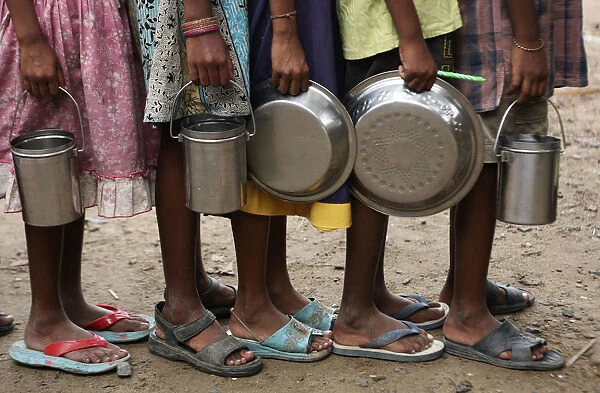 Students stand in a line to collect their free mid-day meals, distributed by a government-run