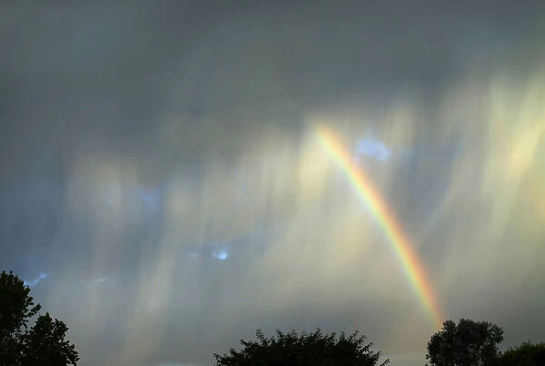 A summer rainbow breaks through an isolated and quickly moving thunderstorm as it passes
