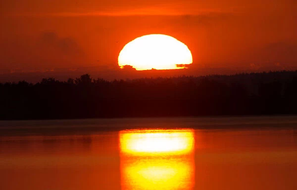 Sun rises behind a lake near the town of Vileika