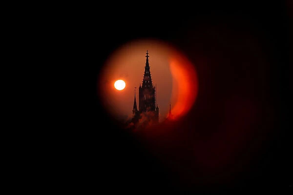The sun rises behind the Muenster Cathedral during a cold morning in Bern