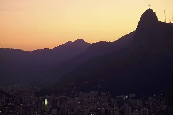 The sun sets behind Christ the Redeemer statue on Corcovado mountain in Rio de Janeiro