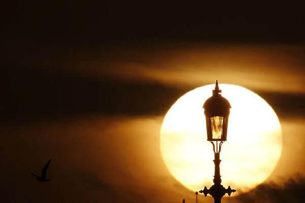 The sun sets behind a lamp in London