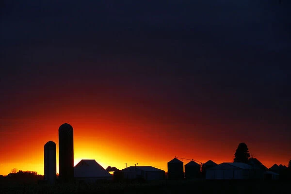 The sun sets over a silhouette of a farm corn silo outside of Rock Rapids