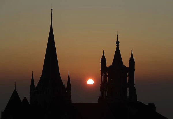 The sun sets on a winter evening between the spires of the Cathedral of Notre Dame in