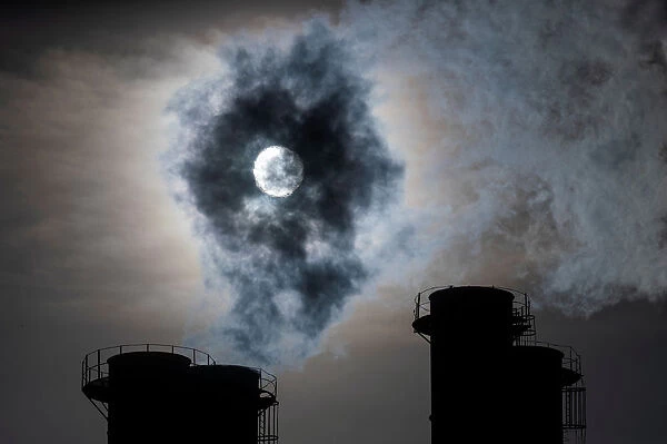 Sun shines through steam rising from chimneys of a power plant in Moscow