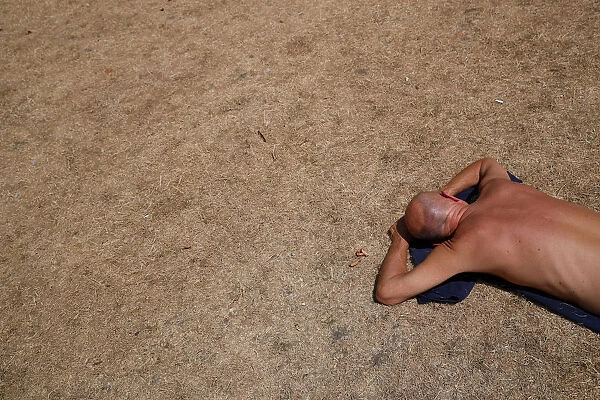 A sunbather lays on the dry grass in St Jamess Park, in central London