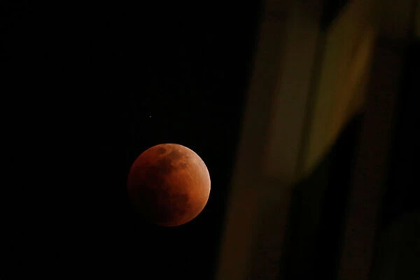 A super blood blue moon is seen during an eclipse, behind an office building in Hong