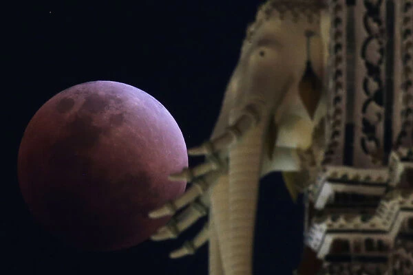 A super blood blue moon is seen during an eclipse behind an elephant statue at a temple