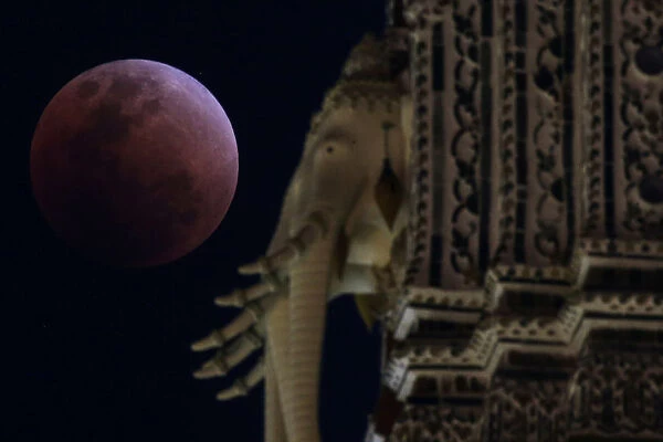 A super blood blue moon is seen behind an elephant statue during an eclipse at a temple