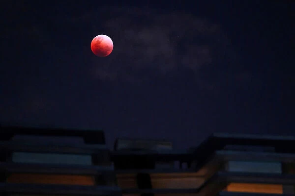 A Super Blue Blood Moon rises over an apartment block during a lunar eclipse in