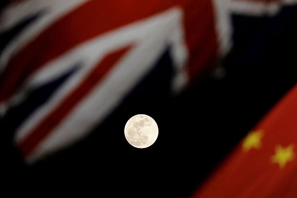 The super blue moon is seen between British and Chinese flags raised at Tiananmen square