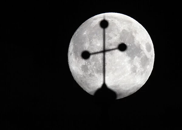 The super moon is pictured behind the cross of a church in Vienna