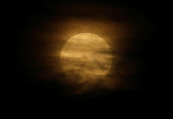 A supermoon full moon is partly obscured by clouds in Pieta