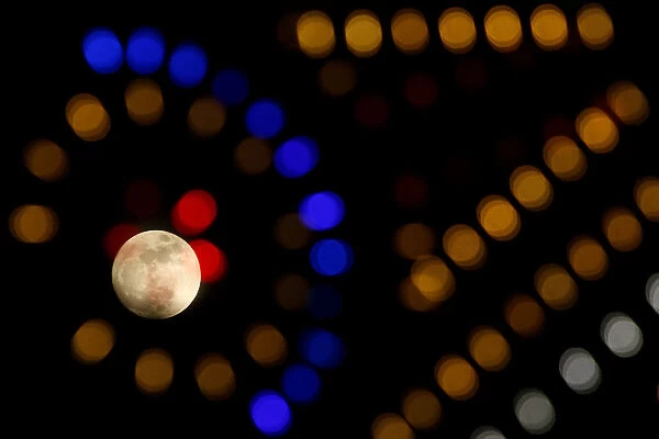 The supermoon full moon is seen through Christmas lights in Valletta