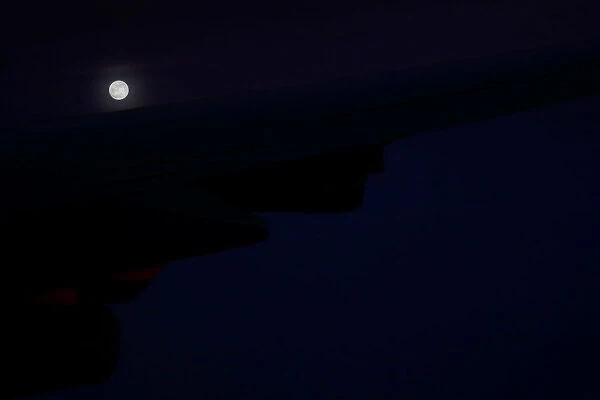 A supermoon full moon can be seen in the distance over the wing of Air Force One