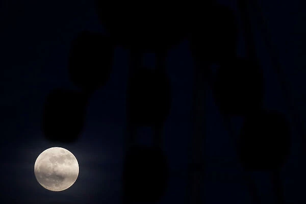 The supermoon full moon is seen rising behind an advertising billboard in Ronda