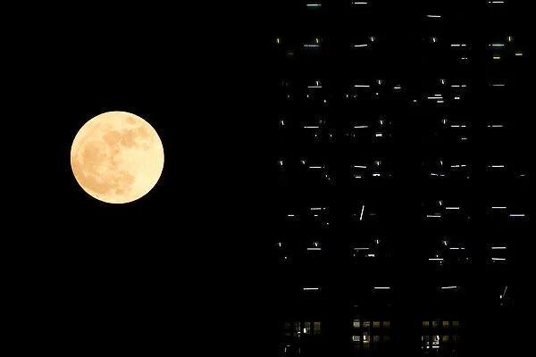 The supermoon is seen behind a building under construction in Hong Kong
