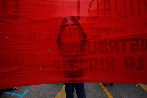 A supporter of the Communist party uses a scissors to make holes on a banner as he takes