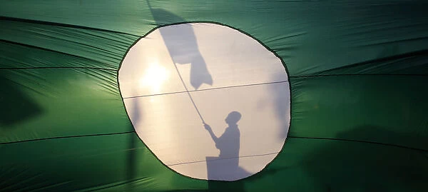 A supporter of opposition PAS is silhouetted on its giant flag as he campaigns on a