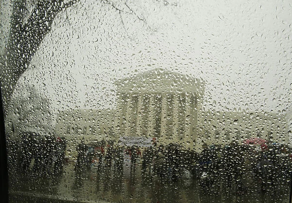 The Supreme Court is seen from within a car as snow melts on the window during a light
