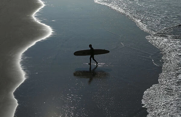 Surfer heads home after riding the morning waves in Oceanside, California