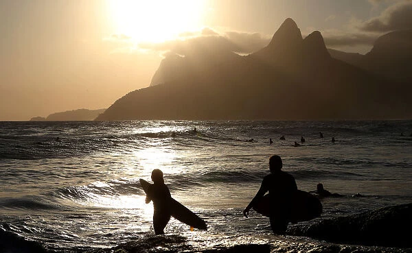 Surfers are seen during a sunset on Arpoador beach in Rio de Janeiro