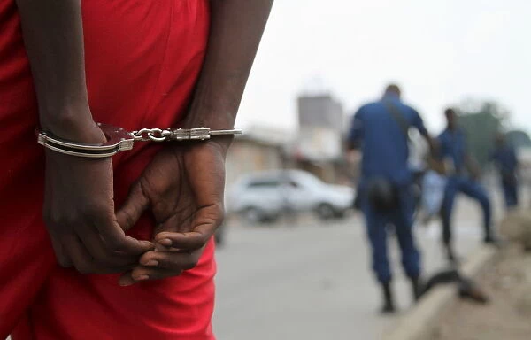 A suspect is handcuffed and detained by policemen after a grenade attack of Burundi s
