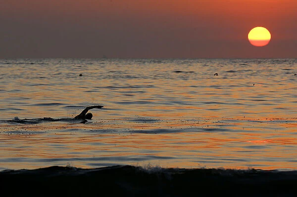A swimmer practices in the waters of Copacabana beach as the sun rises in Rio de Janeiro