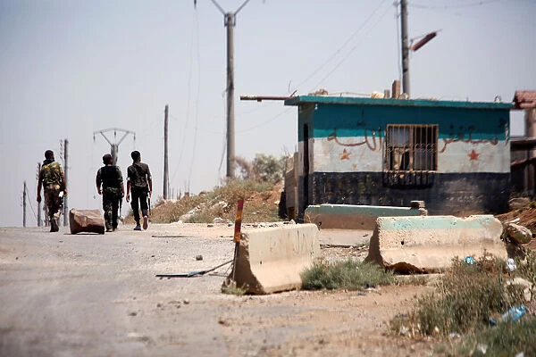 Syrian army soldiers walk along a street in Umm al-Mayazen, in the countryside of Deraa