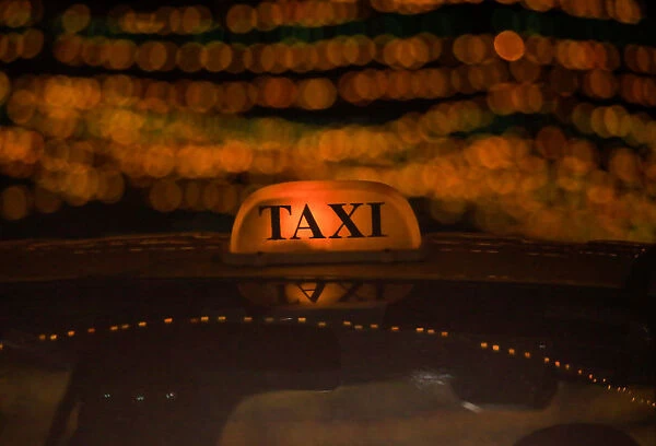 A taxi drives through the street decorated with lights ahead of Tihar festival