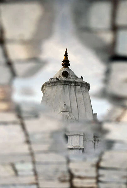 A temple is reflected in a puddle of water on a street after last nights rain in