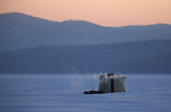 A tent of fishermen is seen on the ice-covered Yenisei River during sunset in the