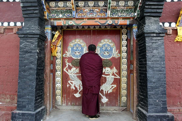 A Tibetan monk closes a door which leads to a temple in the monastery in Tongren