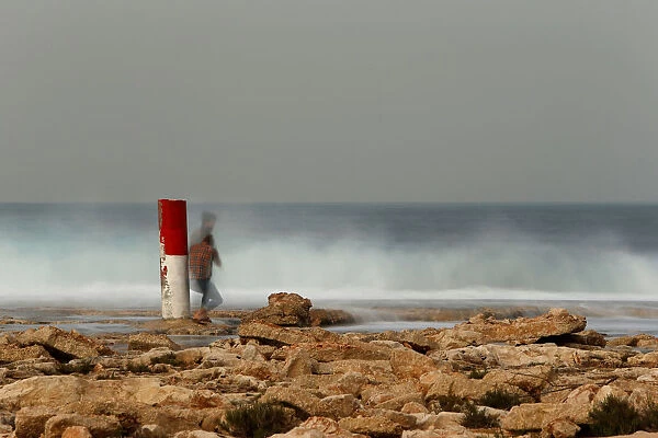 A tourist takes pictures of breaking waves at Ghallis outside Naxxar
