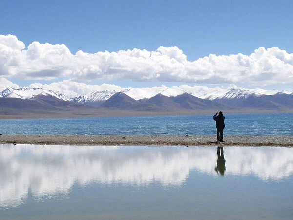 A tourist takes pictures at Namtso lake in the Tibet Autonomous Region