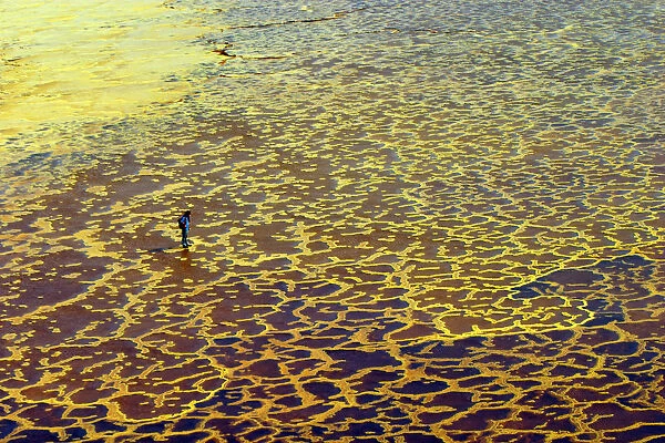 A tourist visits yellow sulphur and mineral salt formations created by upwelling springs