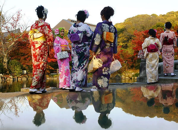 Tourists, dressed in traditional Japanese kimonos, stand in a park in Kyoto