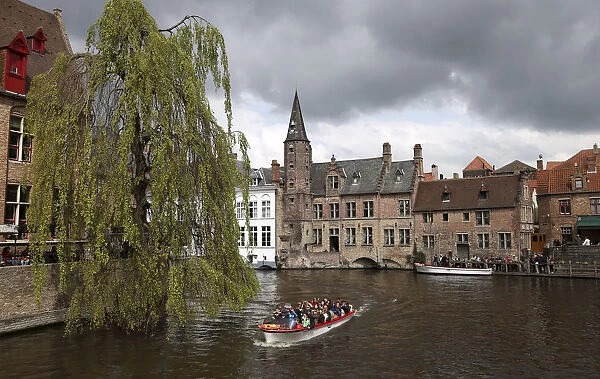 Tourists enjoy a boat ride on a canal of the old town in Bruges