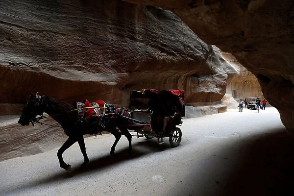 Tourists ride a horse-drawn cart during a tour in the ancient city of Petra, south of Amman