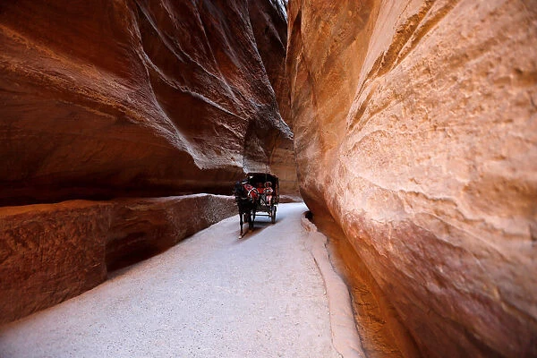 Tourists ride a horse-drawn cart during a tour in the ancient city of Petra, south