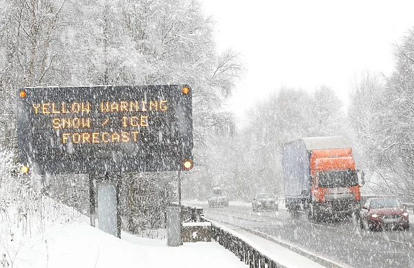 Traffic passes a road sign warning of adverse weather conditions on the A9 near