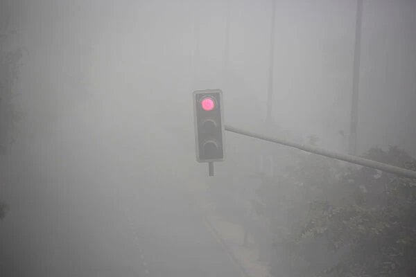 A traffic signal displays a red light during heavy fog in Delhi
