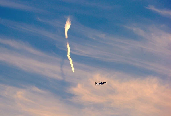 The trail of an aeroplane can be seen amongst clouds and above a plane after it took