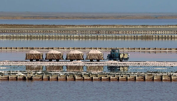 A train drives across the bed of a drained area of a lake used for the production of salt