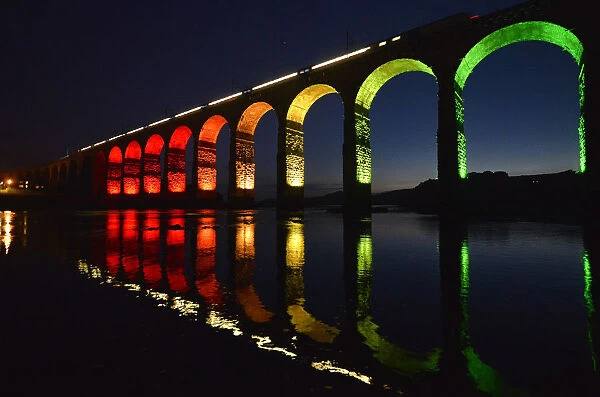 A train is reflected in the River Tweed as it crosses the Royal Border Bridge at dusk