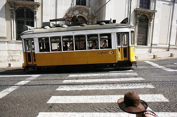 The tram 28 moves past an old building in Lisbon