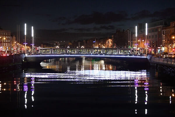 A tram crosses a bridge over the river Liffey at night in Dublin