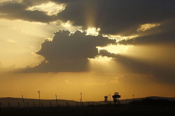 A Turkish border watch tower is silhouetted against the sunset at the Turkish-Syrian