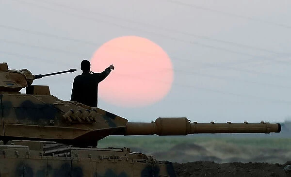 A Turkish soldier points as he stands on a tank during a military exercise near the