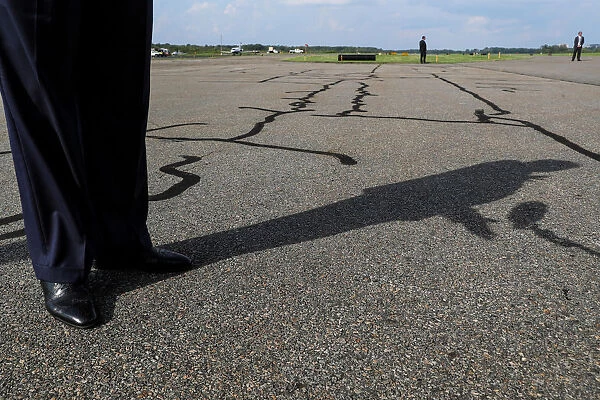 U. S. President Trump casts a shadow on the tarmac as he talks to reporters before